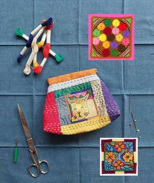 Buntes, besticktes Täschchen, umgeben von Stickgarn, Schere und Stickmustern