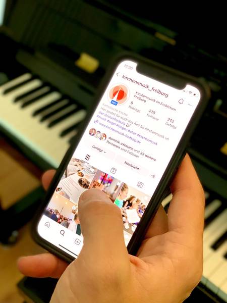 Ein Smartphone mit dem Instagram-Kanal des Amts für Kirchenmusik wird mit dem Daumen bedient.